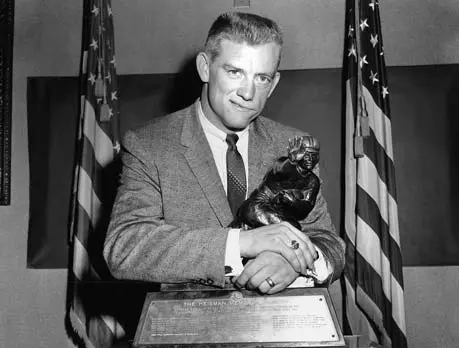 A man in a suit holding a football player statue