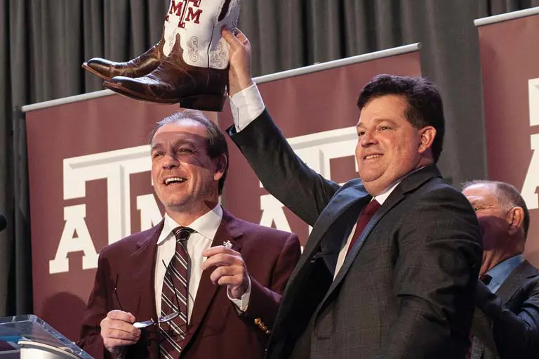 Jimbo Fisher next a man holding up a pair of boots