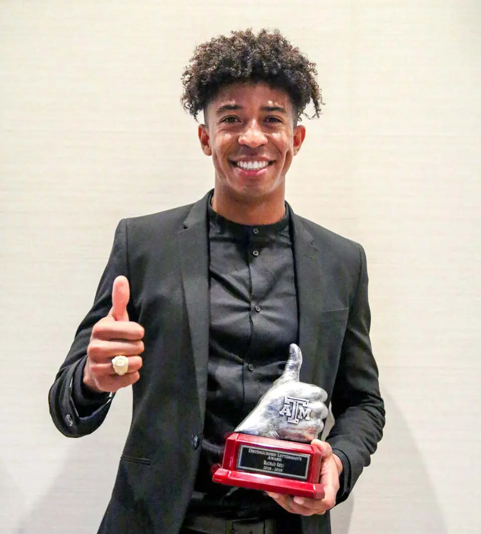 A student-athlete posing with an award