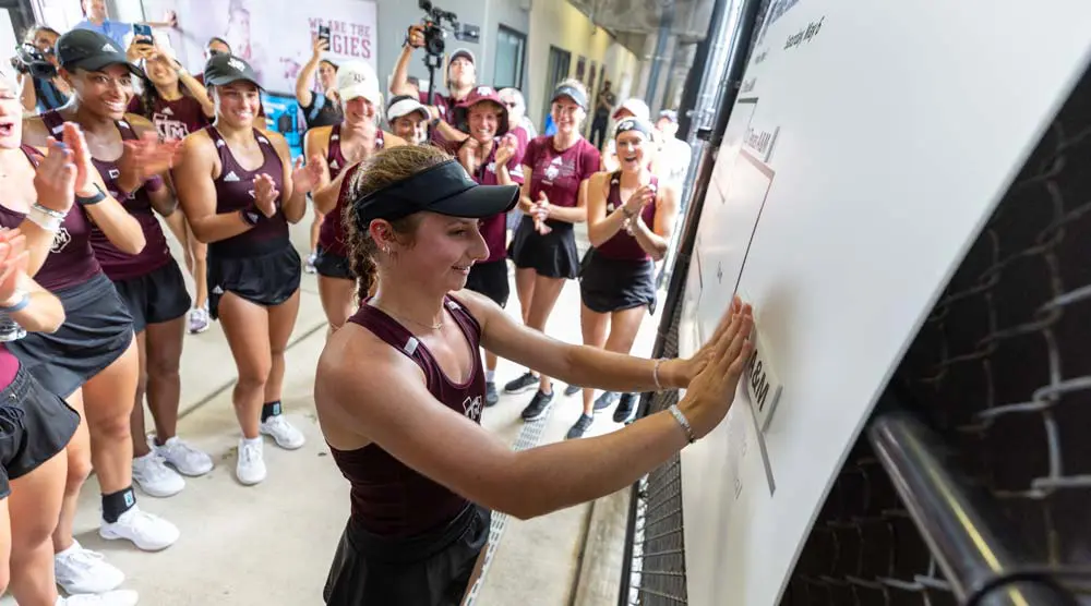 Mary Stoiana at a white board with team mates behind her clapping